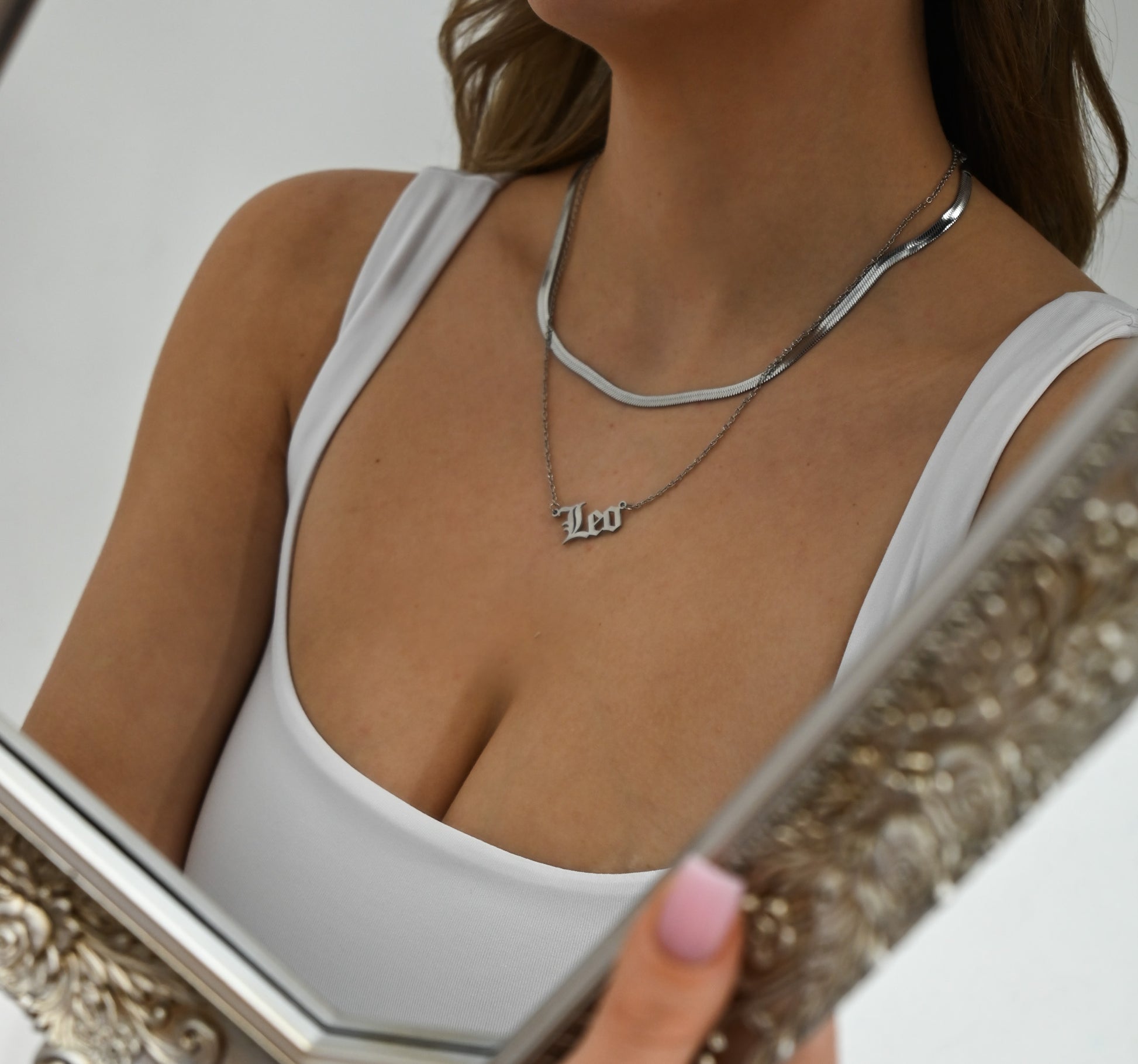 model looking in mirror wearing silver herringbone chain 