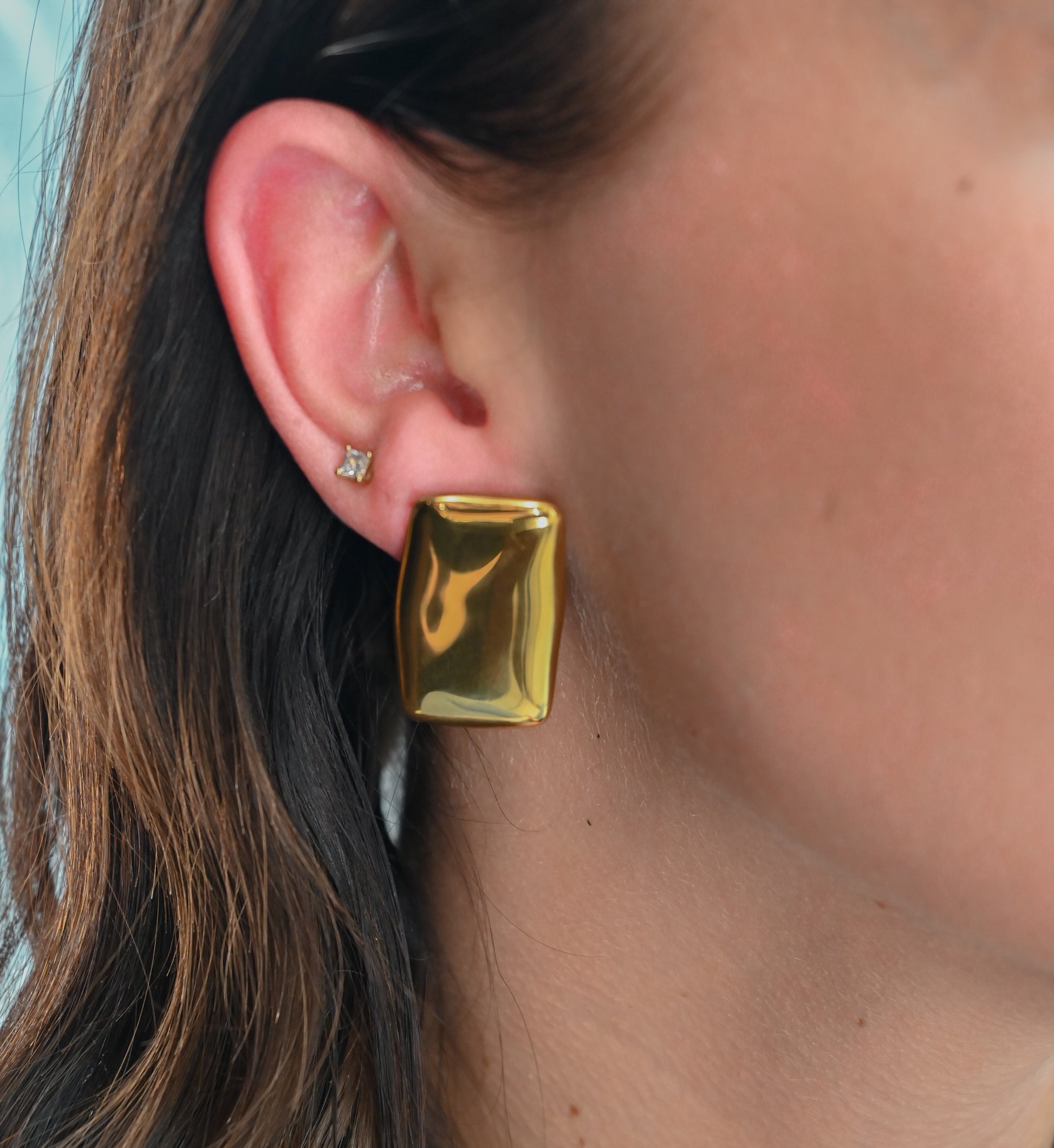 Model wearing large square gold block earrings