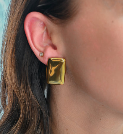 Model wearing large square gold block earrings